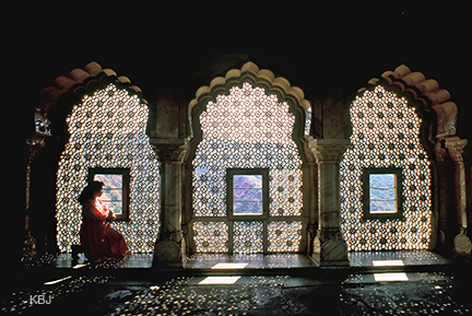 A young tourist looking out through the 'Jharokhas' (narrow windows)  of Amer Palace in Rajasthan, India.