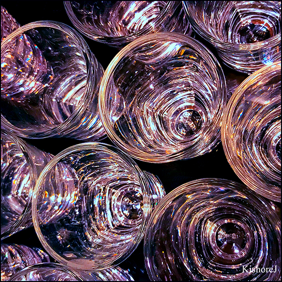 Sparkling glasses at a cocktail party waiting to be filled. Colorful lights all around are reflecting on their surfaces.